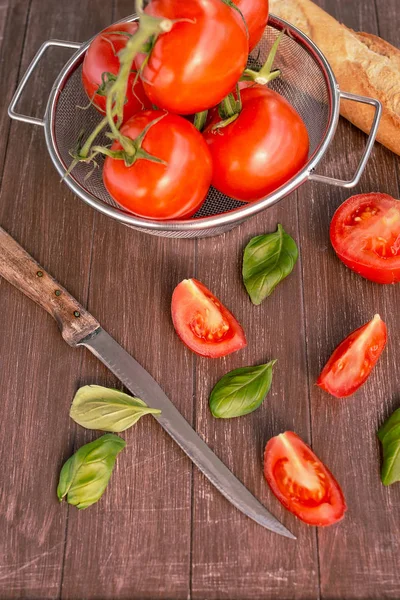 Bir ahşap tepsi bir kapta taze domates ve bir baget yalan