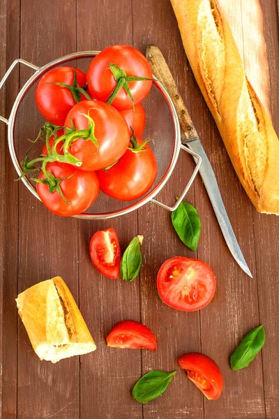 Bir ahşap tepsi bir kapta taze domates ve bir baget yalan