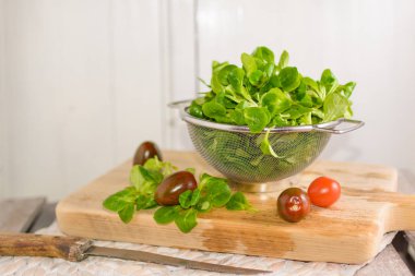 Bir kevgir ve domates mısır salata yalan içinde ahşap tepsi