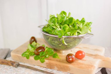 Bir kevgir ve domates mısır salata yalan içinde ahşap tepsi