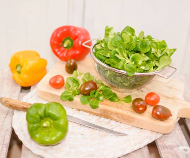 Bir kevgir, biber ve domates yalan bir ahşap tepsi üzerine Mısır salata