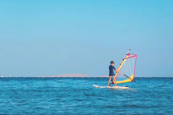 Çocuk açık deniz sularında windsurf öğrenmek