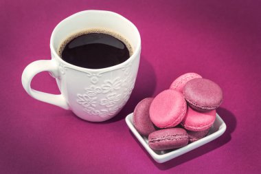 Birkaç lezzetli tatlı pembe beyaz kase ve kopya ile pembe arka plan üzerinde beyaz kupa macaroons closeup uzay