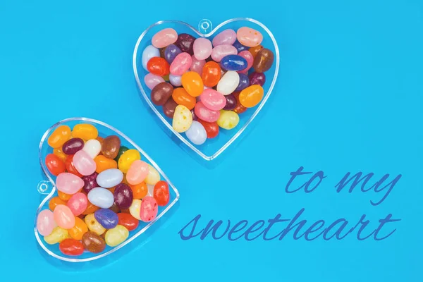Two hearts with candies on blue background with card message to my sweetheart. Love and St Valentines day concept flat lay
