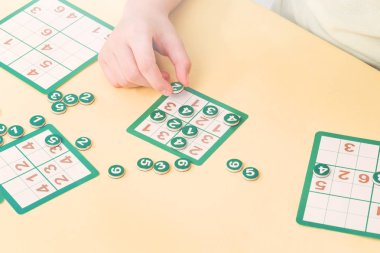 Çocuk sudoku masa kartı numarası belirteçleri ile doldurma oyunu oynar