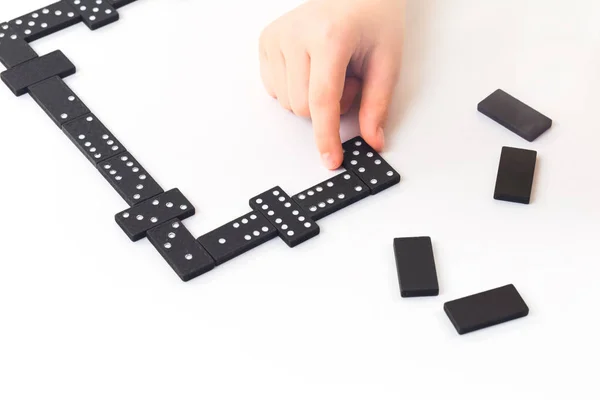Dominoes game. Kids hand is holding a domino tile with some on table. Boardgame concept