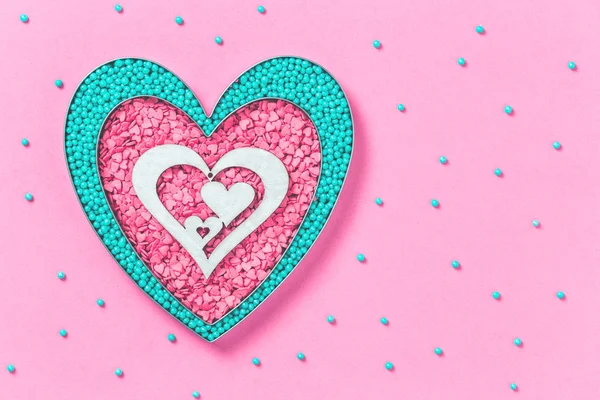 Pink and mint colors cake sprinkles sweets heart shape on pink background with copy space, flat lay. Love, Mother\'s and Valentines Day concept
