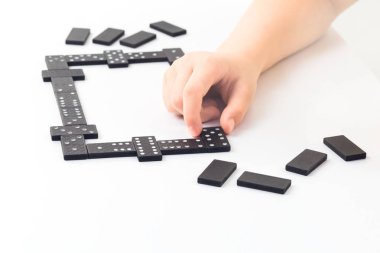 Domino oyunu. Çocuklar el bazı tablo üzerinde bir domino taşıyla tutuyor. Boardgame kavramı