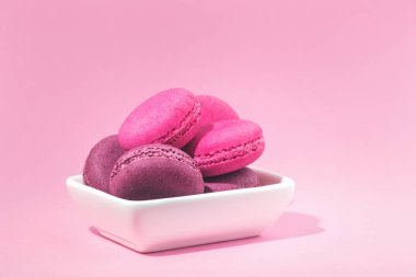 Birkaç tatlı lezzetli pembe macarons kopya alanı closeup ile pembe arka plan üzerinde beyaz kase