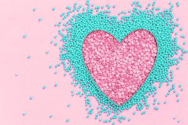 Pink and mint colors cake sprinkles sweets heart shape on pink background with copy space, flat lay. Love, Mother\'s and Valentines Day and charity concept