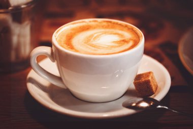 Bir kahve fincanı latte sanat ve kahverengi şeker küpü ile