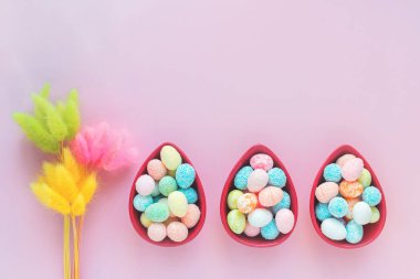 Mutlu Paskalya parlak tebrik kartı üç yumurta küçük yumurta ile çanaklar, düz lay uzayda kopya ile pembe arka plan üzerinde şeklinde