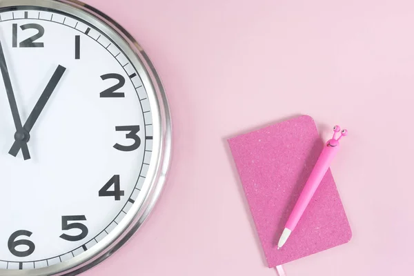 Частина настінного годинника з рожевим блокнотом і ручкою — стокове фото