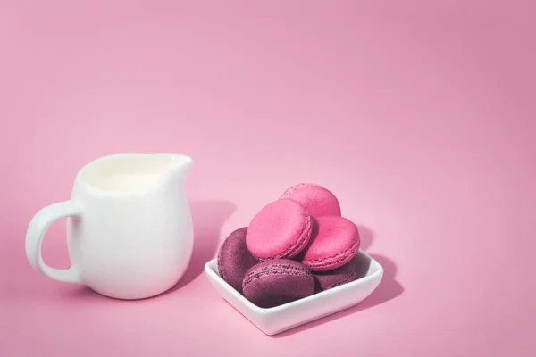 Mehrere leckere rosa Makronen in Schüssel und Milchglas — Stockfoto