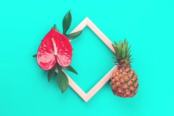 Pineapple, flower and leaves frame on mint background