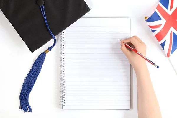 Black graduation cap with notebook isolated