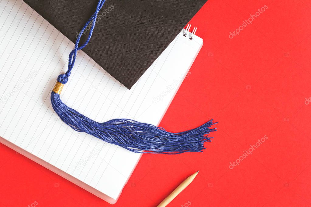 Black graduation cap with blue ribbon on red