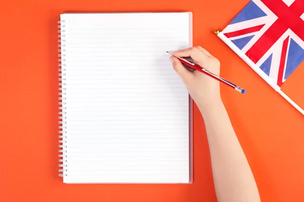 Händerna med en penna med styrde anteckningsblock på orange — Stockfoto