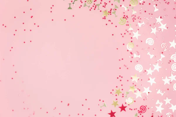 Confetti festivi spumeggianti dorati assortiti su rosa — Foto Stock