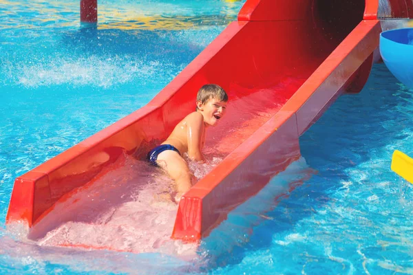 Joyeux garçon caucasien joyeux sur la glissière d'eau au parc aquatique — Photo