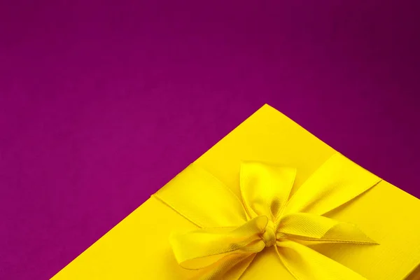 Boîte-cadeau jaune vif sur fond rose foncé — Photo