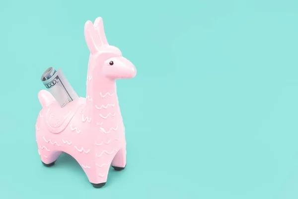 Pink toy llama money bank on blue background