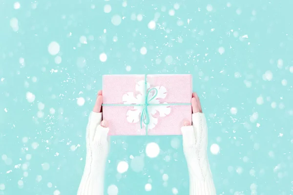 Manos en manoplas con caja de regalo de invierno con copo de nieve — Foto de Stock