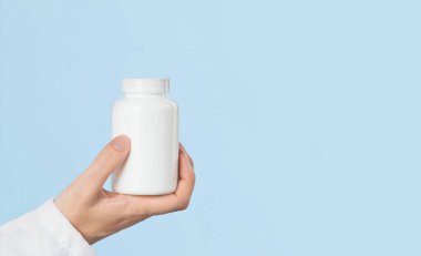 Kadın doktorun elinde beyaz haplar ya da tablet kavanozunun maketi var. İlaç ve eczane, reçeteli ilaçlar veya vitamin konsepti. Boşluk afişini kopyala