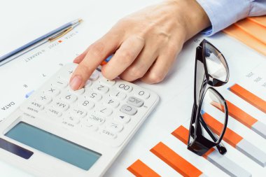 Finans ve iş konsepti. Finansal grafiklerde hesap makinesiyle el, gözlüklü ya da gözlüklü. Muhasebe bütçesi ya da piyasa analizi. Ev finansmanı.