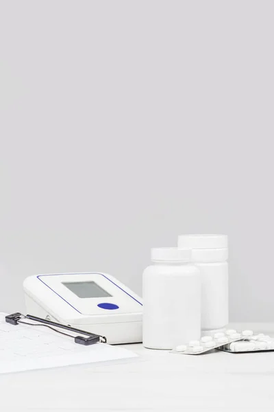 医学和药学背景 单色灰色背景下的药丸和血压监测器 调味白瓶 医学概念 复制空间 — 图库照片