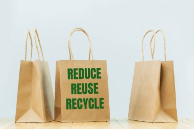 REDUCE RECYCLE metnini açık kağıda tekrar kullan. Gri üzerinde çantalar taşı. Mal ve bakkal teslimatı, alışveriş kuryesi. Çevre dostu ambalaj, plastik ücretsiz servis. Alışveriş ve satış. Boşluğu kopyala