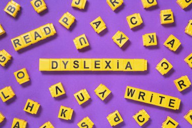 Disleksi, pembe mor üzerine sarı yazılar yaz etrafa dağılmış harf küpleri, okuma güçlüğü ve bozukluk görsel ve işitsel hafıza veya test konsepti. Kopyalama alanı olan eğitim nörolojisi