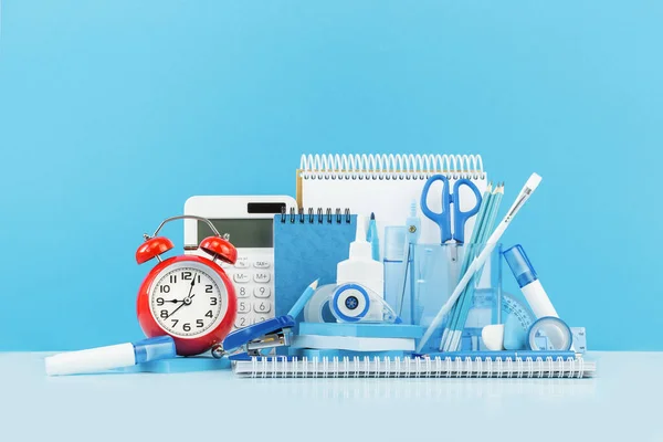 オフィス用品や学校の青の文房具や机の上に赤い目覚まし時計のグループ 学校や教育や工芸の概念に戻るためのバナー 時計と計算機 選択的フォーカス コピースペース バナー — ストック写真