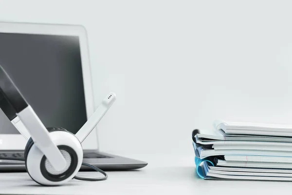 Kapatın. Boş ekranlı, kulaklıklı, beyaz masalı ve not defterli bir laptop. kopyalama alanı. Uzaktan öğrenme ya da evden çalışma, çevrimiçi kurslar, alışveriş asgari konsept. Yardım masası çağrı merkezi