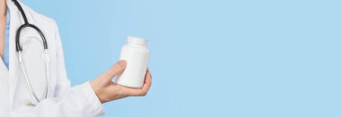 Kadın doktorun elinde beyaz haplar ya da tablet kavanozunun maketi var. İlaç ve eczane, reçeteli ilaçlar veya vitamin konsepti. Boşluk afişini kopyala