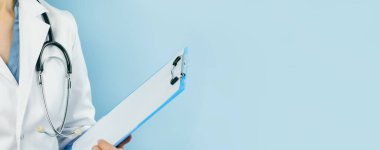 Beyaz üniformalı beyaz bir kadın doktor elinde boş bir dosya tutuyor. İlaçlar. Mavi web pankartı. Uzayı kopyala Model veya şablon