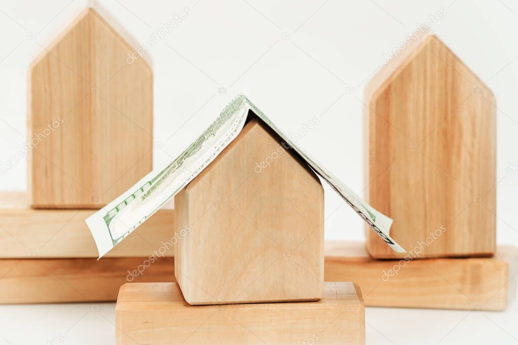 Wooden building blocks houses close up with dollar bill roof. Mortgage rates and loans. Real estate rentals and Insurance. DIY constructions. Mockup