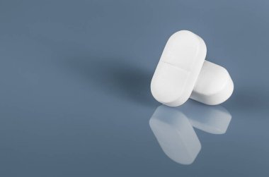 Mavi bardağa yansıyan iki beyaz tablet ya da hap. Alan yakın görüntüsünü kopyala. İlaç güvenli tüketim ve tedavi, aşı ve aşılama. İlaç, sağlık ve eczane konsepti