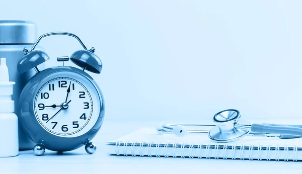 Medical or healthcare concept monochrome banner. Red alarm clock with stethoscope on top of pile of spiral notepad. Medical study research, checkups paperwork. Doctor appointment. Copy space.