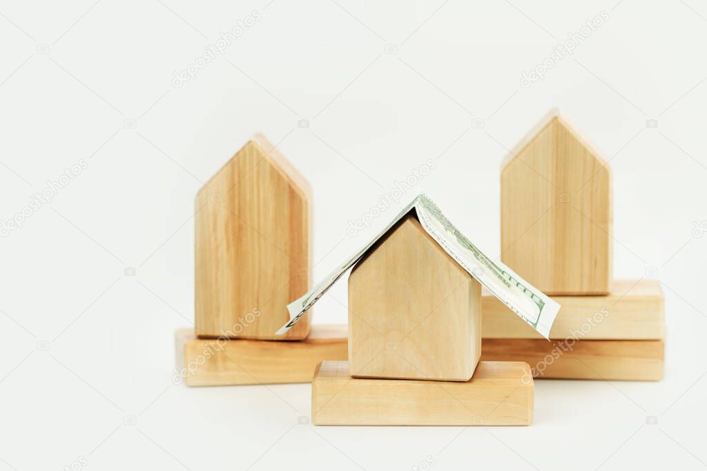 Wooden building blocks houses with dollar bill roof. Mortgage rates and loans. Real estate rentals and Insurance. DIY constructions. Mockup