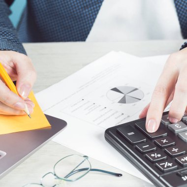 Finans ve iş konsepti. Dişi küçük işletmeler. Masa ve dizüstü bilgisayardaki mali grafiklerde hesap makinesiyle el ele. Muhasebe bütçesi ya da piyasa analizi. Ev ekonomisi. Krediler