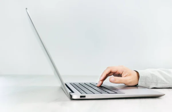 灰色桌子上的薄银色笔记本电脑的侧面视图 女性的手使用笔记本电脑键盘 复制空间 最低限度 — 图库照片