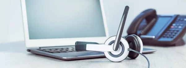 İş ve iletişim. Laptop ve vop telefonları ofiste. Giyin ya da online konferans yap. Bilgisayar masanın üstünde. IP telefonu, soğuk telefon. Ofis işi ya da öğrenme. Web Afişi