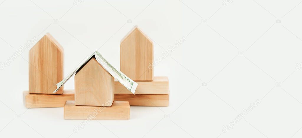 Wooden building blocks houses with dollar bill roof. Mortgage rates and loans. Real estate rentals and Insurance. DIY constructions. Mockup banner. Copy space