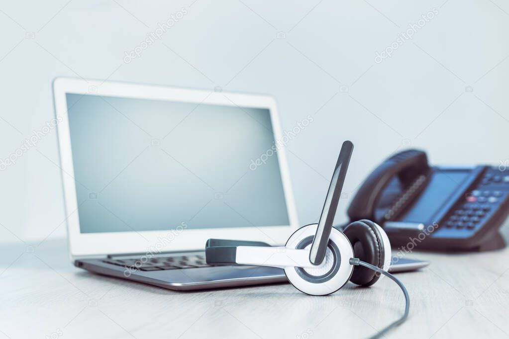 business and communications. Mockup laptop and voip phone in the office. Webinar or online conference. laptop with headset on desk. IP telephony, Cold calling. Office work or learning. Copy space