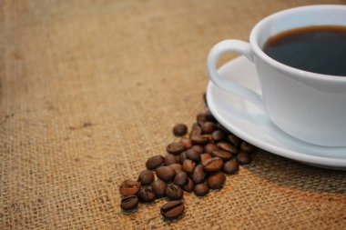 Beyaz porselen fincan fasulye çuval bezi arka plan üzerinde siyah kahve