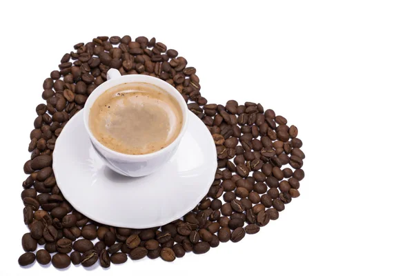 Изолированная чашка кофе на зернах, разбросанных по форме сердца — стоковое фото