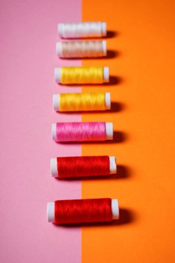 Parlak çift renkli pembe ve turuncu zemin üzerine dikiş için renkli konu kümesi.