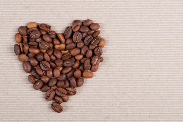 Grãos de café torrados formando uma forma de coração . — Fotografia de Stock