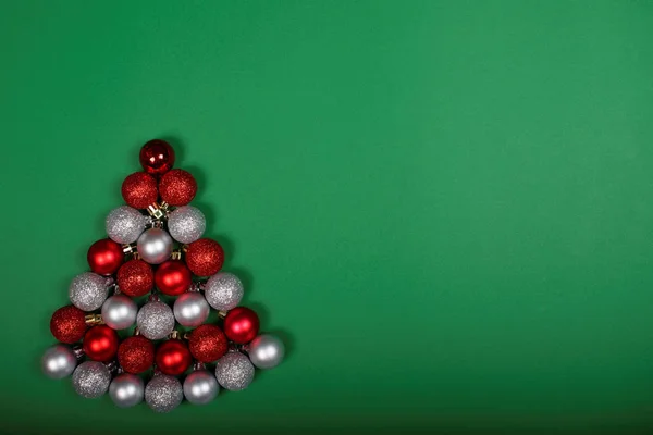 Baubles formando albero di Natale su sfondo verde — Foto Stock